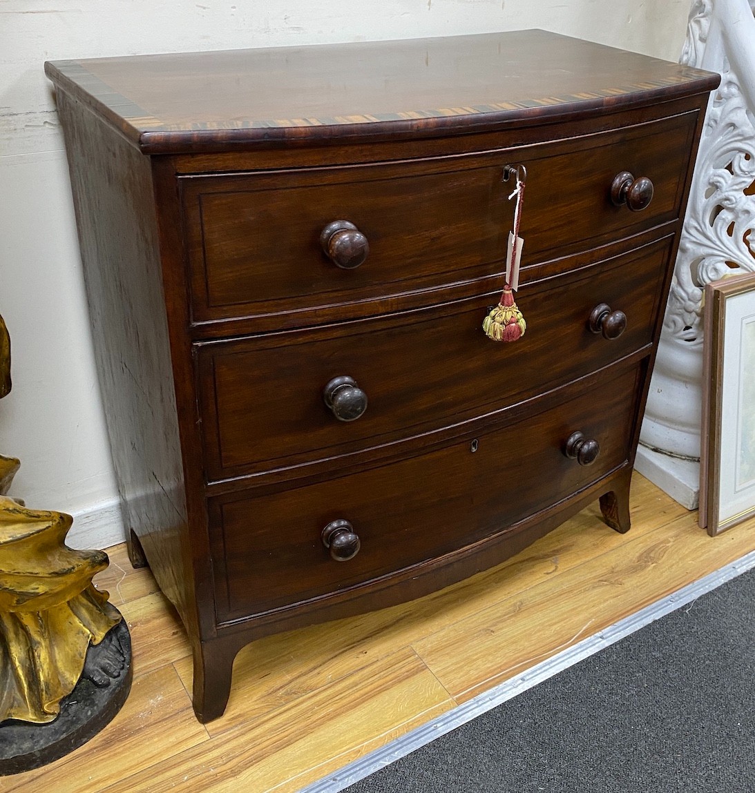 A late Regency coromandel banded mahogany bowfront chest of three drawers, height 85.5cm, width 86cm, depth 47cm